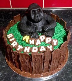 a birthday cake with a gorilla sitting on top of grass and the words happy birthday