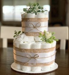 a three tiered cake made out of diapers with flowers and greenery on top