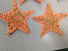 three orange and gold stars with donuts on them sitting on a table next to each other