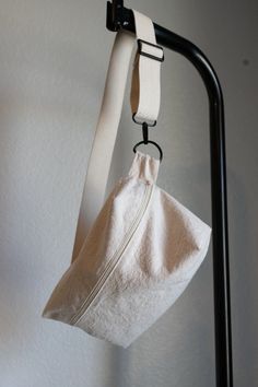 a white bag hanging from a hook on a wall with a black metal pole holding it