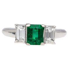 an emerald and diamond three stone ring with two baguets on each side, in white gold