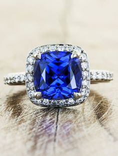 a blue cushion cut sapphire surrounded by diamond halos on a white gold wedding ring