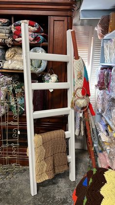 a ladder leaning up against a wall in a room filled with fabrics and other items