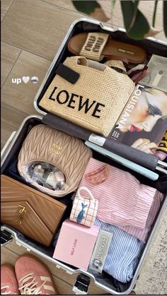 an open suitcase filled with personal items on top of a tiled floor next to a plant