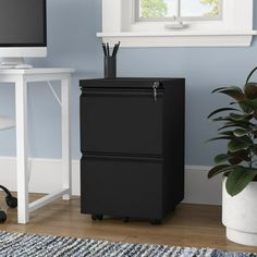 a black filing cabinet sitting in front of a computer monitor on top of a desk