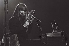 a woman holding flowers while standing next to a piano and microphone in front of her