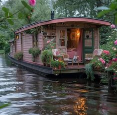 a houseboat is floating down the river with flowers on it's deck and windows