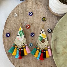 Add a touch of elegance to your outfit with these stunning Golden Kite Leather and Colorful Tassel Bohemian Earrings. Crafted from two layers of leather, these earrings feature a larger kite-shaped piece in a shiny gold color, adorned with smaller kite shapes in shades of green, yellow, red and white, each showcasing beautiful floral designs. The earrings are finished with long, silk tassels in pink, yellow, black, red, blue and green, perfectly complementing the floral designs. These boho-chic African Earrings, Long Fringes, Chic Leather, Bohemian Earrings, Leather Tassel, Fringe Earrings, Tassel Earrings, Leather Earrings, Gifts For Wife