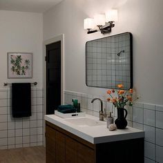 a bathroom with white and black tiles on the walls, wooden cabinets and a sink