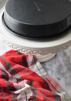 a black lid on a white casserole dish with red and green plaid napkins