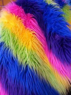 a multicolored furry pillow is on display in a store window, with the colors of rainbows and blue