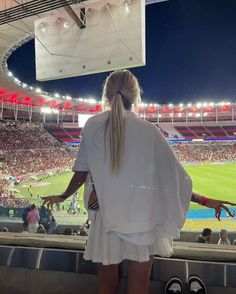 a woman standing in front of a stadium filled with people