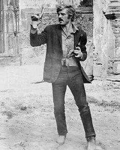 black and white photograph of a man holding something in one hand while standing on dirt ground