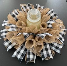 a wreath made out of burlocks with a mason jar on the front and bottom