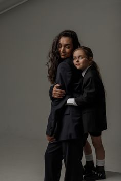 a woman and child hugging each other in front of a gray background