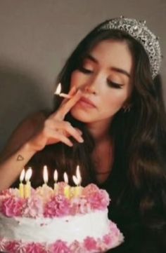 a woman sitting in front of a cake with lit candles