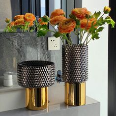 two vases with flowers in them sitting on a counter top next to a mirror