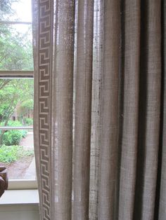 an open window with curtains and a vase in front of it on the windowsill