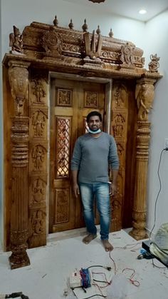 a man standing in front of a wooden door with carvings on the wall and floor