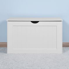 a white storage box on carpeted floor with blue wall