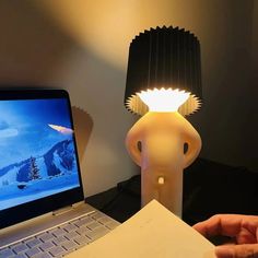 a laptop computer sitting on top of a desk next to a light that is shaped like an elephant