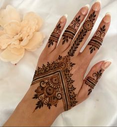 a woman's hand with henna tattoos on it and flowers in the background