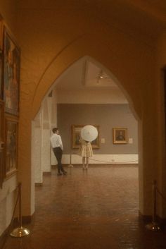 two people standing in an art gallery looking at artwork on the walls and paintings on the wall