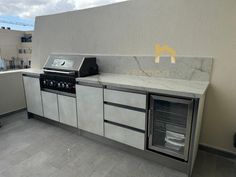 an outdoor kitchen with stainless steel appliances and tile flooring on top of a roof