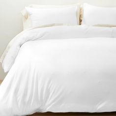 a bed with white sheets and pillows in a room