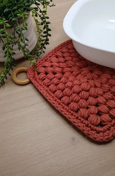 an orange crocheted placemat next to a white bowl