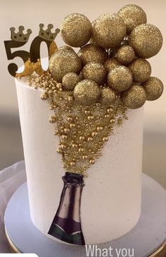 a white cake with gold decorations and a bottle of champagne on the top that says 50 what you love