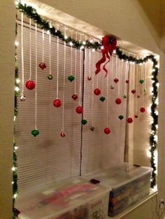 a window with christmas decorations hanging from it's sides and lights on the windowsill