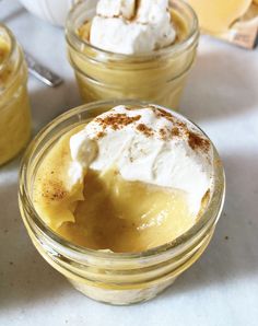 two desserts in small glass jars with whipped cream on top