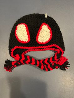 a crocheted hat with red eyes and a striped scarf around the brim