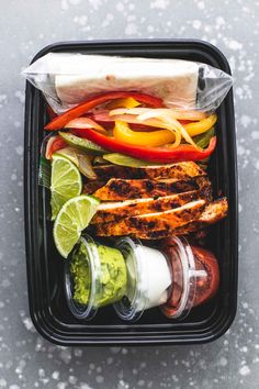 a container filled with meat, vegetables and sauces