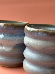 two ceramic bowls sitting side by side on a pink tableclothed surface, one with white and blue glaze