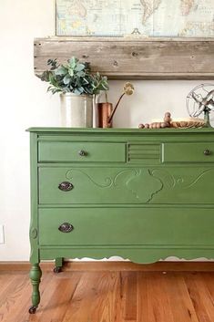 a green dresser sitting on top of a hard wood floor next to a wall mounted map