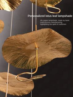 the cover of an art book with gold leaves hanging from it's sides and two metal hooks attached to them