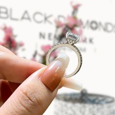 a person holding a ring with a diamond on it's middle finger, in front of a white background