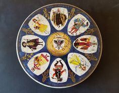 a blue plate with pictures of different people painted on the front and sides in gold trim