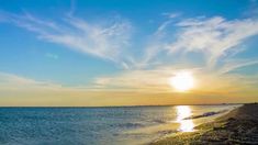 the sun is setting over the water at the beach