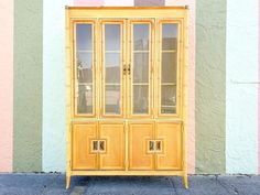 a yellow china cabinet sitting in front of a colorful wall