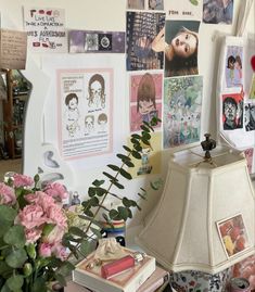 a lamp sitting on top of a table next to a vase filled with pink flowers