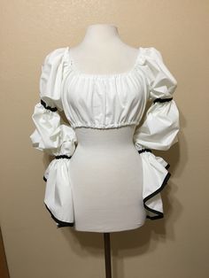 a white dress on a mannequin with black trims and ruffled sleeves