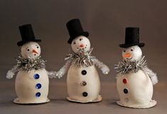 three snowmen wearing hats and scarves are standing next to each other in front of a gray background