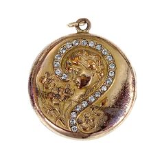 "Question mark jewelry seems to have been a popular novelty around the turn of the twentieth century. When the trends of the heavier and more somber Victorian era came to an end, the Art Nouveau period began. Inspired by nature, the aesthetic was airier and more fluid, incorporating more light-hearted subject matter. This whimsical locket has repousse designs of a beautiful lady gazing at a small bunch of flowers. A paste diamond question mark encircles her head, as if she is asking, \"Does he love me?\". An antique photograph of a woman is enclosed inside (possibly the previous owner), giving us a little peek into the past!  No question about it, this is one little keepsake you'll treasure in your collection! Details (approximate) Dimensions: 1.5\" Materials: Gold filled metal; Paste diam Gold Engraved Jewelry For Vintage Events, Engraved Gold Jewelry For Vintage Events, Art Deco Engraved Jewelry For Vintage Events, Art Nouveau Jewelry With Historical Design For Formal Events, Historical Medallion Jewelry For Weddings, Historical Medallion Design Jewelry For Wedding, Antique Yellow Gold Jewelry For Vintage Events, Medallion Jewelry With Historical Design For Weddings, Art Deco Jewelry With Antique Finish As Gift