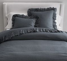 a bed with blue linens and ruffled pillows