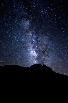 the night sky is filled with stars and bright lights, as well as silhouettes of mountains