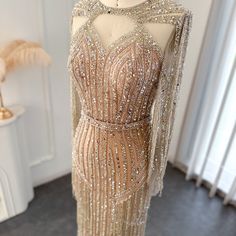 a dress on display in front of a white table with a vase and lamp behind it