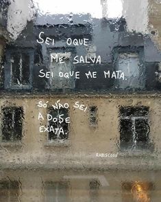 the words are written on the window in front of the building and rain is coming down